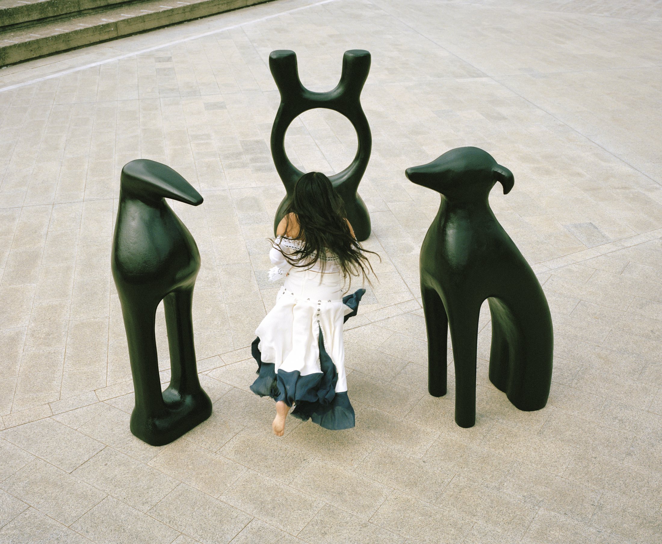 BLUEM framed by three dark sculptural forms on stone.